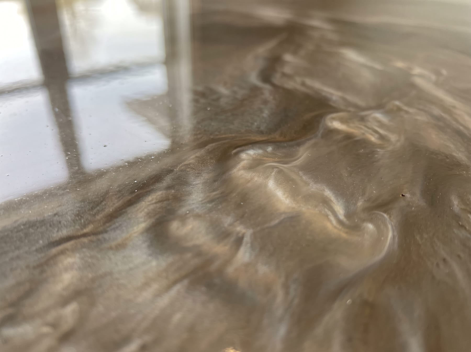 Close-up of a metallic epoxy floor showing pearlescent swirls and shifting light