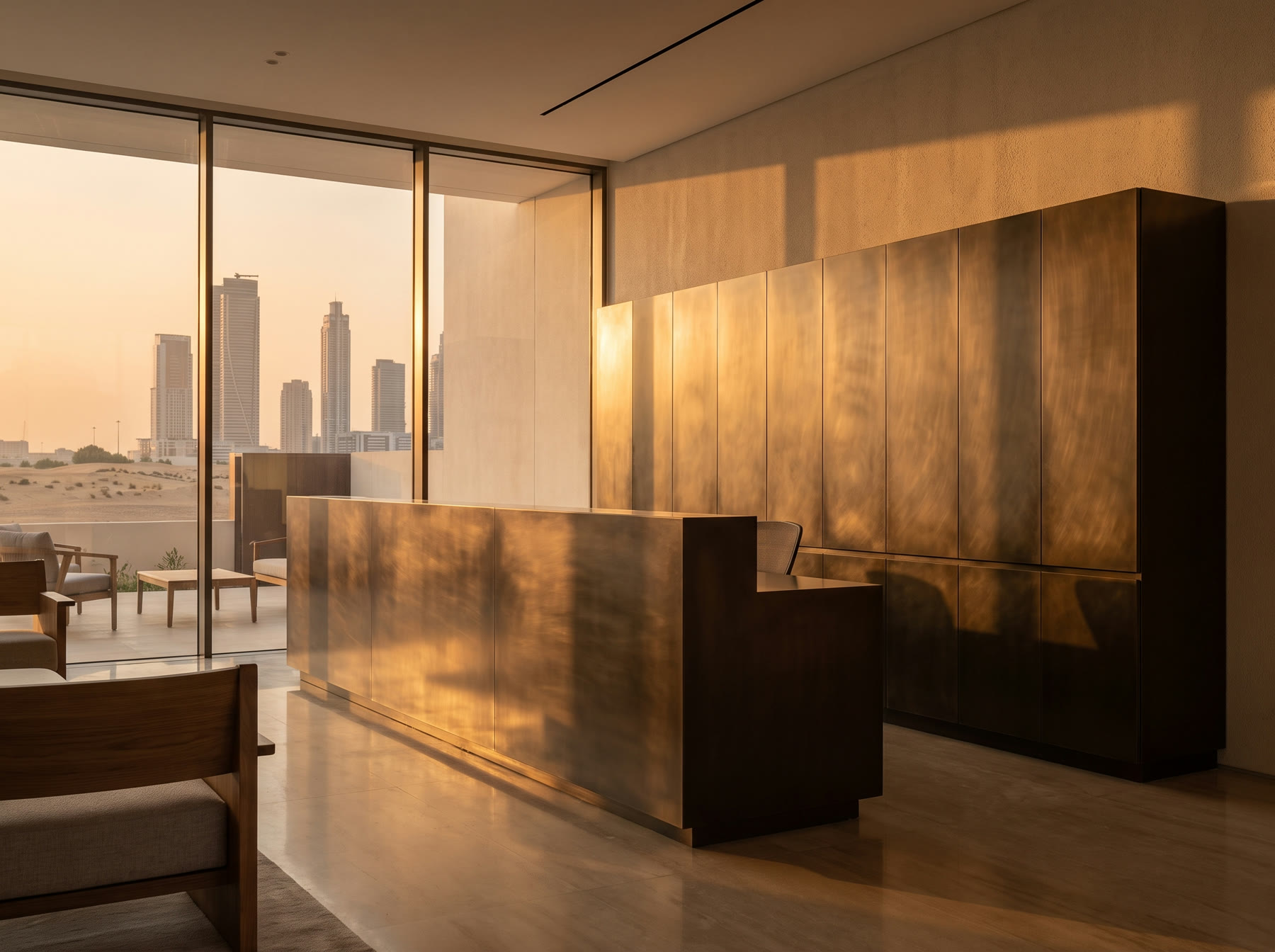 Bronze-toned cabinetry and a curved reception desk in a bright room with a city skyline through the windows at sunset